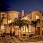 Mediterranean stucco home at dusk with aluminum windows and palm trees