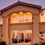 Mediterranean-style home at dusk with vinyl patio doors and windows