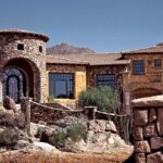 Mediterranean stone home with wood-clad windows and a turret